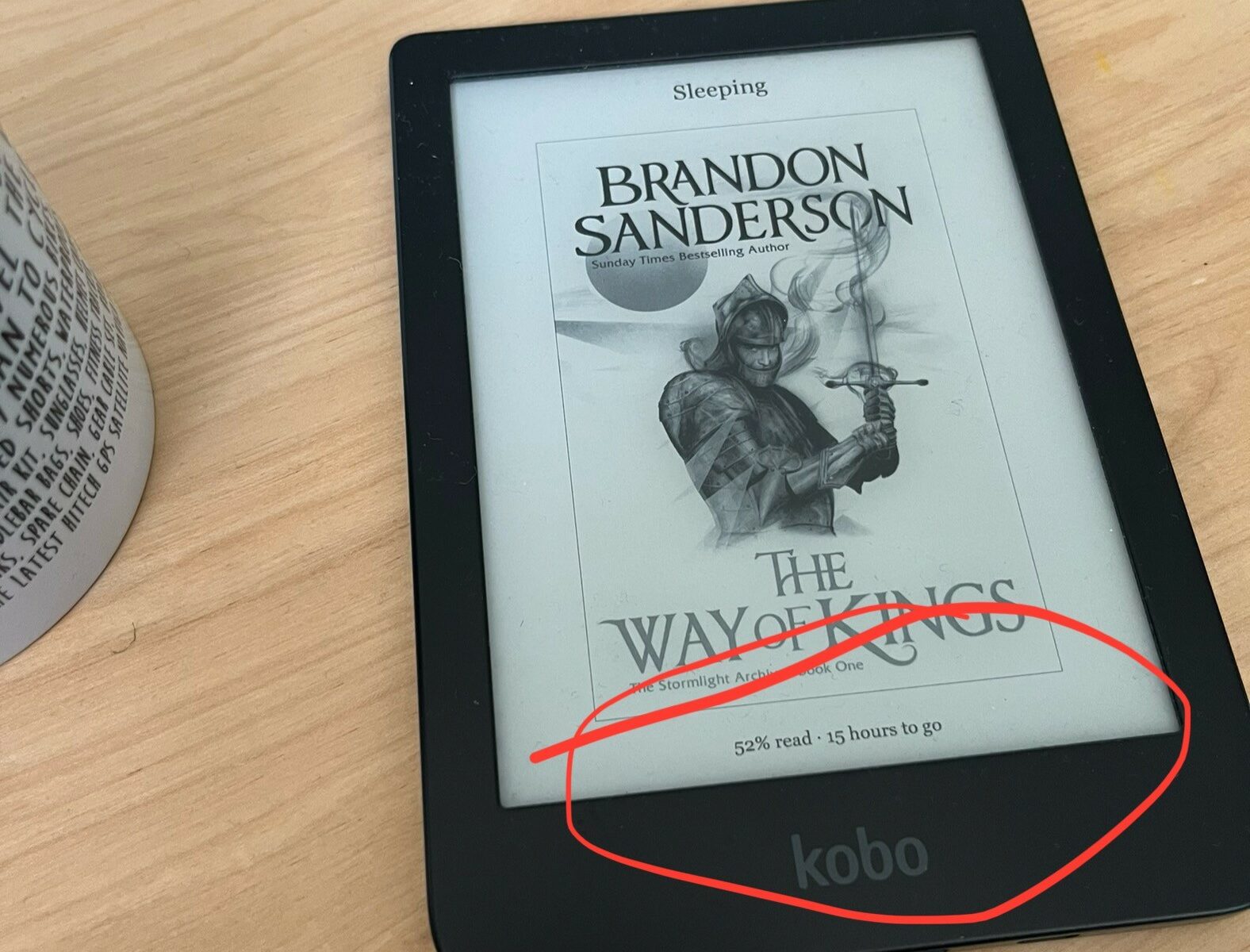 My Kobo eReader sits on a table. The cover screen shows Brandon Sanderson’s The Way of Kings. I have proudly highlighted that it says I’m 52% read.