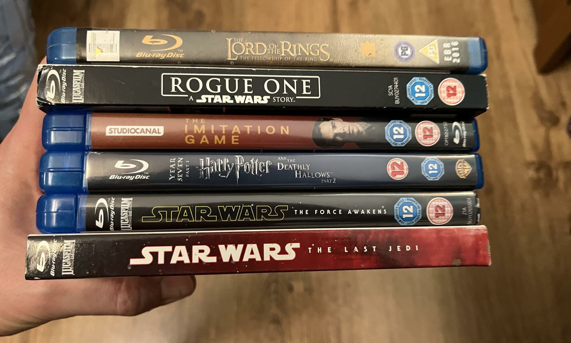 A stack of Blu Ray discs in their boxes including several Star Wars movies, a Harry Potter, and The Imitation Game.